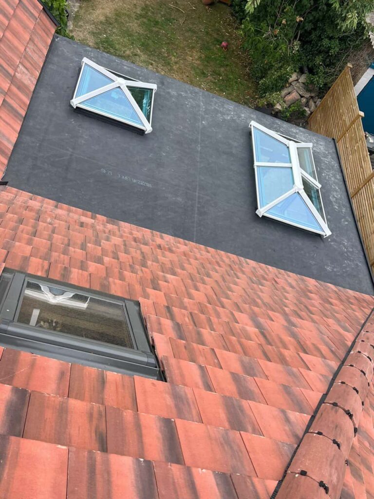 This is a photo taken from the roof ridge looking down a tiled pitched roof on to a flat roof. Works carried out by Upper Stoke Roofing Repairs